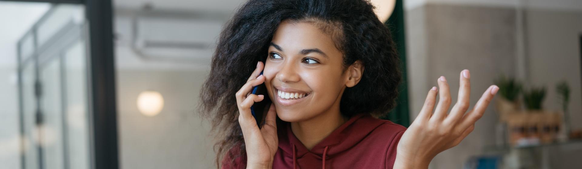 Jeune femme souriante au téléphone a obtenu un mini prêt GMF pour un besoin ponctuel de trésorerie